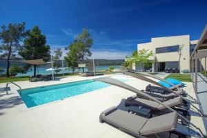 una piscina con due sedie a sdraio di fronte a una casa di Villa Lagoon a Vourvourou