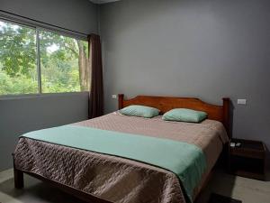 a bedroom with a bed with a large window at Uvita Stone House in Uvita