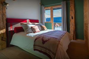 a bed in a room with a window and a bedspread at La Ferme des Artistes - OVO Network in Mieussy