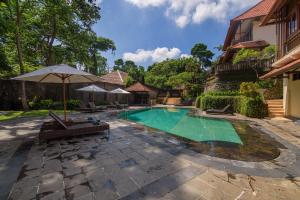 a swimming pool with chairs and an umbrella next to a house at Champlung Sari Hotel and Spa Ubud in Ubud