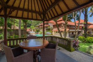 an outdoor patio with a wooden table and chairs at Champlung Sari Hotel and Spa Ubud in Ubud