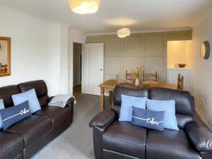 a living room with two leather couches and a table at Dartmoor View in Stoke Gabriel