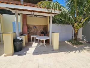 un patio con una mesa y una palmera en casa c/piscina enseada guaruja en Guarujá