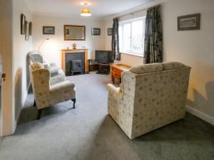 a living room with two chairs and a fireplace at Bournstream Cottage in Withycombe