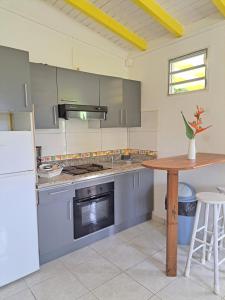 eine große Küche mit einem Tisch und einem Kühlschrank in der Unterkunft Gîte 2 à 4 personnes à la campagne in Le Moule