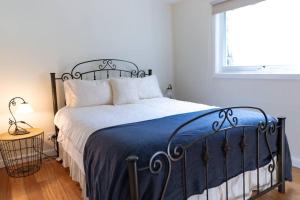 a bedroom with a bed with a blue blanket and a window at Paddys Creek Retreat in Upwey