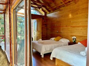a bedroom with two beds in a wooden cabin at San José del Pacífico Camino al Cielo C3 in San Jose del Pacifico