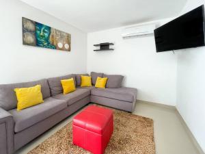 ein Wohnzimmer mit einem grauen Sofa mit gelben Kissen und einem roten Stuhl in der Unterkunft Prime Location House at Cerritos GREAT PRICE in San Rafael