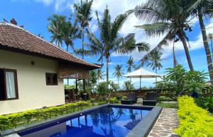 a villa with a swimming pool and palm trees at Lafyu Bali in Singaraja