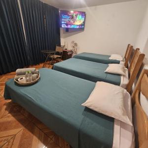 Habitación con 3 camas y TV en la pared. en Lima Airport Hostel with FREE AIRPORT PICK UP en Lima