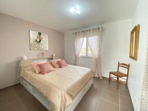 a bedroom with a bed with pink pillows and a chair at Pretty holiday home in Cotentin in Gouville-sur-Mer