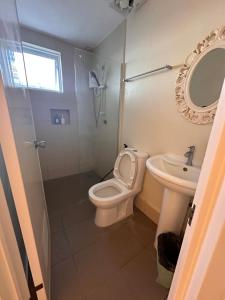 uma casa de banho com um WC, um lavatório e um espelho. em CasaDel Beach House em Mabini