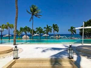 a swimming pool with palm trees and the ocean at Seven Secrets by Hanging Gardens in Senggigi