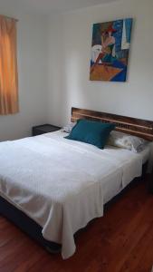 a bedroom with a white bed with a painting on the wall at Cabaña amoblada in Chillán