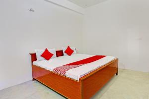 1 cama con almohadas rojas y blancas en una habitación en OYO Flagship City Light Hotel en Kānpur