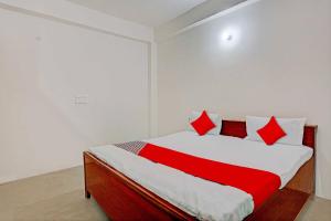 Un dormitorio con una cama con almohadas rojas. en OYO Flagship City Light Hotel en Kānpur
