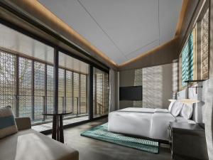 a bedroom with a bed and a table and a couch at Banyan Tree Suzhou Shishan in Suzhou