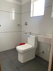 a white bathroom with a toilet and a sink at Misty Avenue Premium Rooms in Anachal