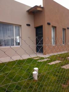 a fence in the grass in front of a building at La casita de Fran in Comandante Luis Piedra Buena