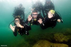 a group of people in the water making peace signs at Praia dos Anjos Residence Clube - O melhor de Arraial do Cabo in Arraial do Cabo