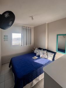 um quarto com uma cama azul e uma janela em DE FRENTE PRO MAR na Praia Grande