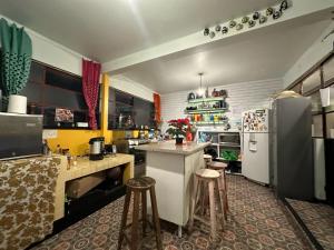 a kitchen with a refrigerator and a counter with stools at Casa Eufemia Hostel type in Mexico City