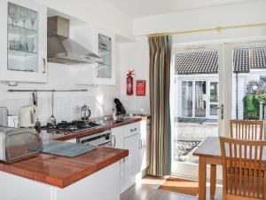 cocina con armarios blancos, fregadero y ventana en Saltbox 5, en Yarmouth