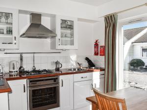 cocina con armarios blancos y fogones en Saltbox 5, en Yarmouth
