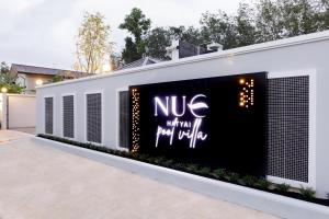 Nue Hatyai Pool Villa في هات ياي: مبنى أبيض مع علامة نيو عليه