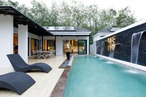 Nue Hatyai Pool Villa في هات ياي: رجل يمشي في بيت فيه مسبح