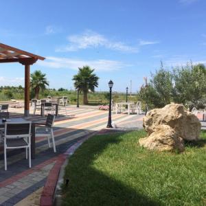 a park with tables and a rock in the grass at Real Resort Albania in Fushë-Draç
