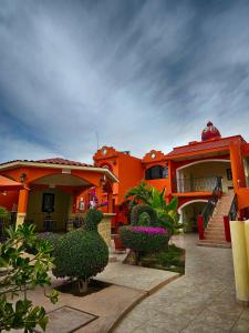 una casa naranja con arbustos delante de ella en Hotel Oasis, en Ciudad Constitución