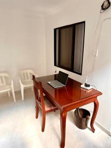 a laptop sitting on a wooden desk with a television at APARTAMENTO FERROCARRIL 201 in Ibagué