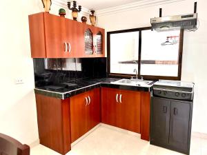 a kitchen with wooden cabinets and a sink and a window at APARTAMENTO FERROCARRIL 201 in Ibagué