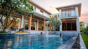 two people in the swimming pool of a house at Memories Holiday beach villa Da Nang in Danang