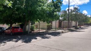 una calle con una valla y un coche rojo estacionado en Etels House - Departamentos Mina Clavero en Mina Clavero