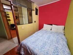 ein Schlafzimmer mit einem Bett und einer roten Wand in der Unterkunft Jaichi Saitama in Cajamarca