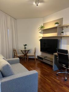 sala de estar con sofá, TV y mesa en Flat Premium -Acesso a pé ao shopping Center vale - Edifício Summit (Ar condicionado) en São José dos Campos