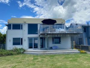 a large house with a balcony with an umbrella at Ultimate Beach Front in Waimarama