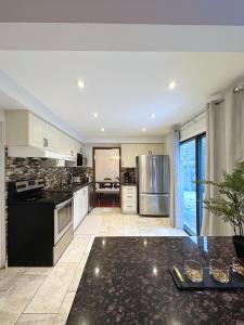 a large kitchen with black counter tops and stainless steel appliances at Elegant Spacious 4BR House in Upscale Neighborhood in Richmond Hill