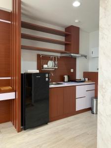 a kitchen with a black refrigerator and wooden cabinets at Golf Resort View at Kaina Tower Nuvasa Bay 9B22 in Nongsa
