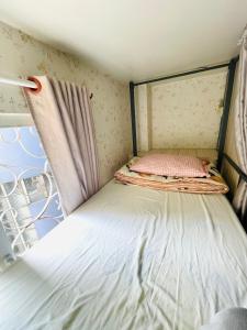 a small bed in a room with a window at LATALAND HOSTEL in Ho Chi Minh City