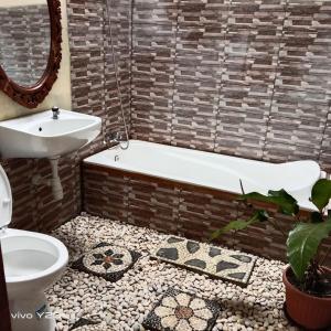 a bathroom with a tub and a toilet and a sink at Villa Mak Cik in Yogyakarta