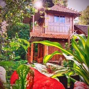 a wooden house with a red flower in front of it at Villa Mak Cik in Yogyakarta