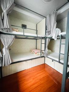 a room with three bunk beds and a wooden floor at LATALAND HOSTEL in Ho Chi Minh City