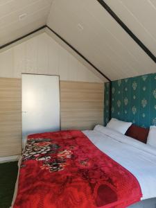 ein Schlafzimmer mit einem großen Bett mit einer roten Decke in der Unterkunft KASANA CLUB MUSSOORIE in Masuri