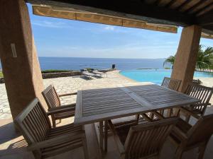 une table et des chaises en bois sur une terrasse avec une piscine dans l'établissement Villa avec piscine à débordement et climatisation, Côte d'Azur - FR-1-768-71, aux Issambres