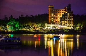 Miracolo View Hotel في يوشيه: مبنى كبير على الماء في الليل