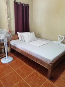 una camera con un letto, un ventilatore e un tavolo di Carmelita Beach Homestay a El Nido