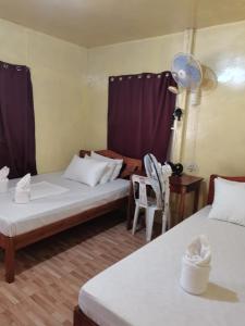 una camera con due letti e una sedia di Carmelita Beach Homestay a El Nido